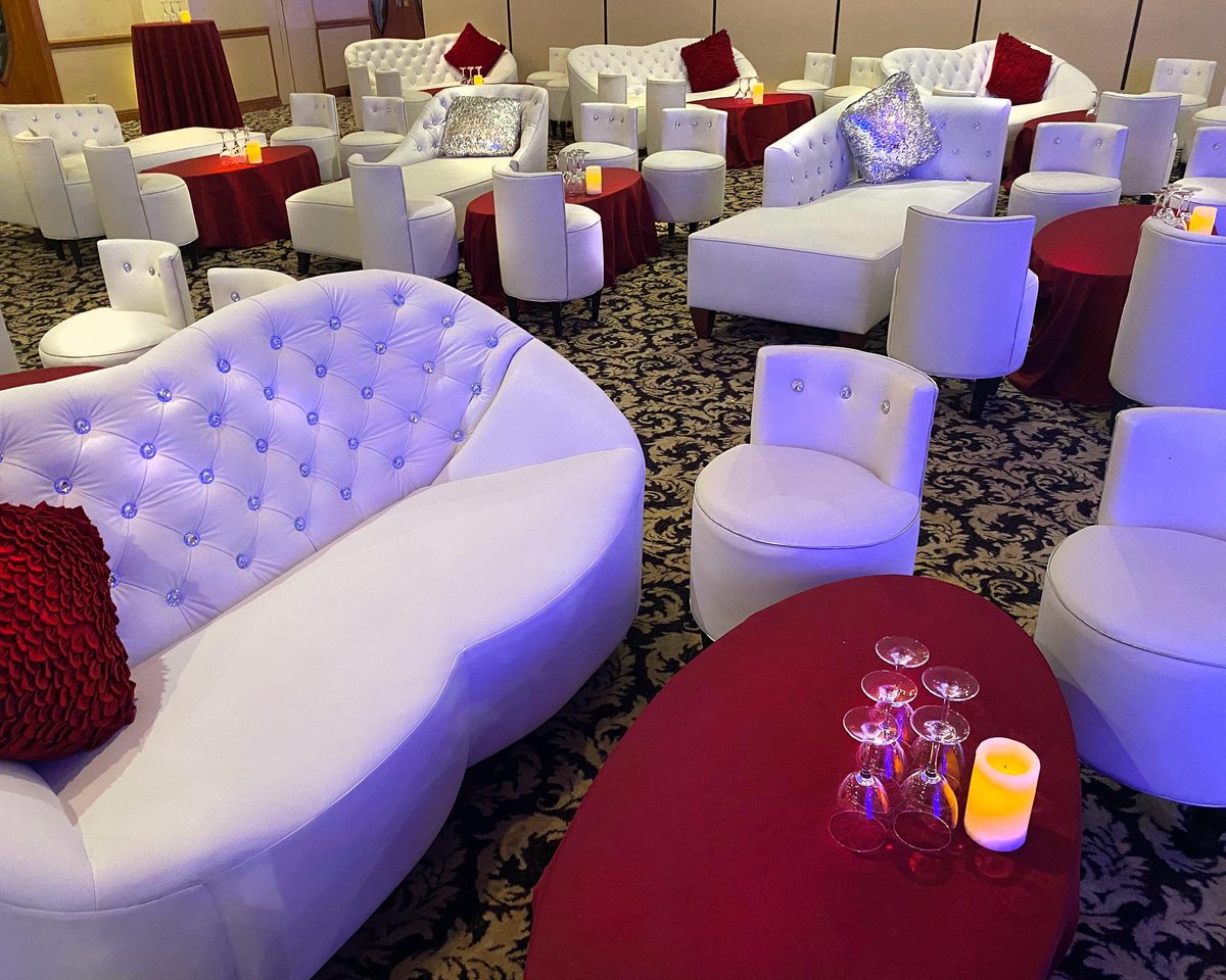 Sala lounge blanca con mesas en rojo y velas