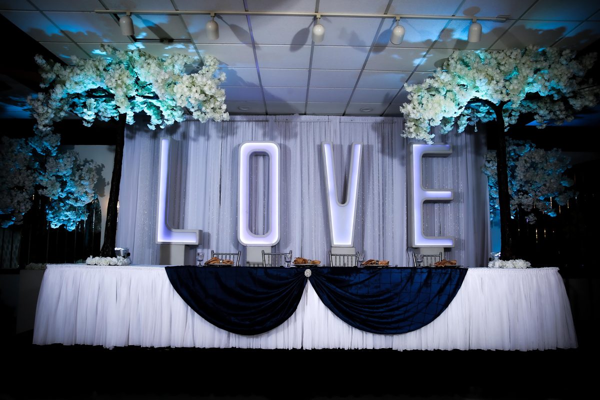 Letras LOVE iluminadas detrás de la mesa principal de una boda