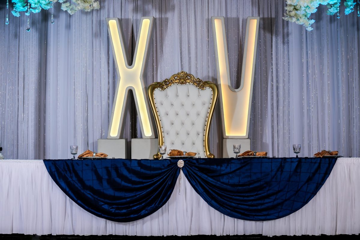 Letras XV iluminadas y silla trono en mesa principal azul marino