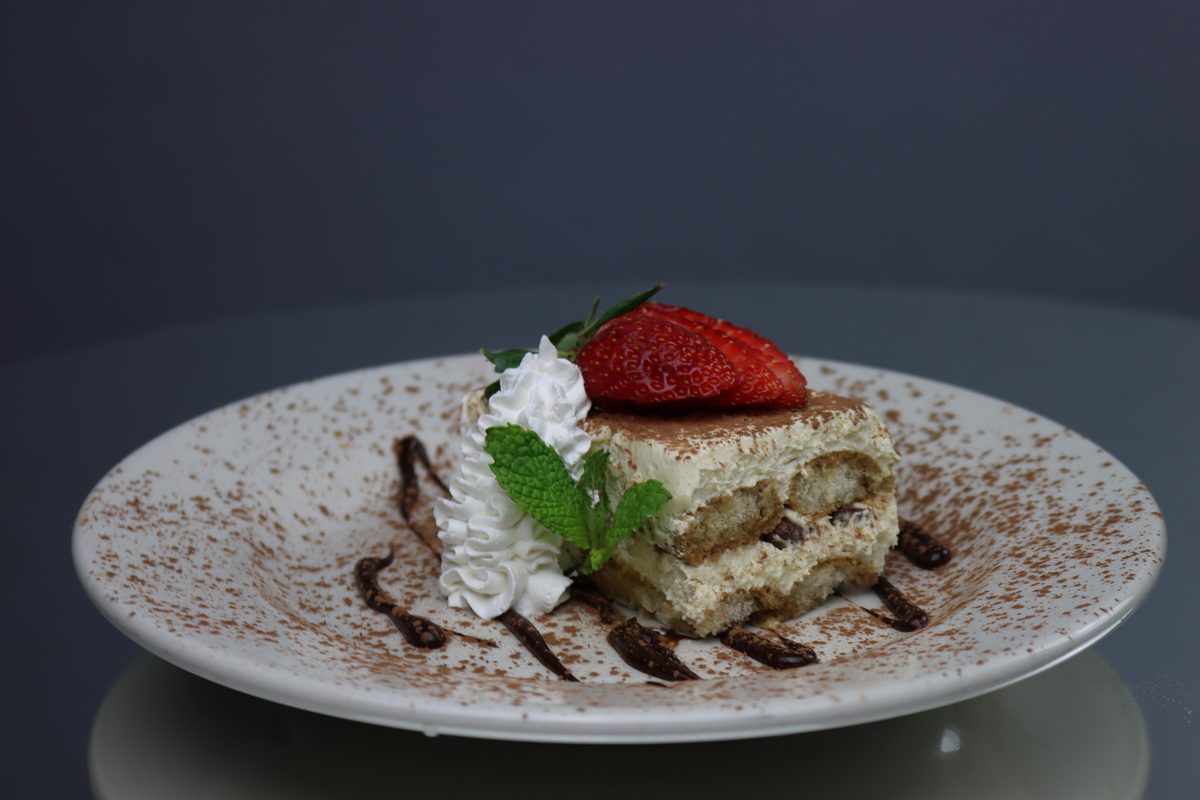 Tiramisú servido con fresa y crema batida